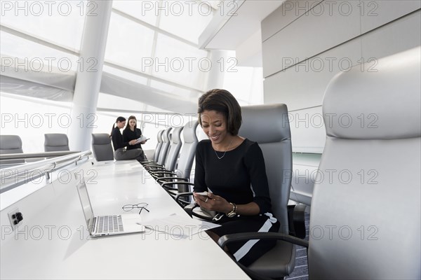 Businesswoman using cell phone in conference room
