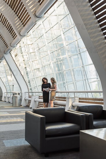 Caucasian businesswomen holding paperwork and talking