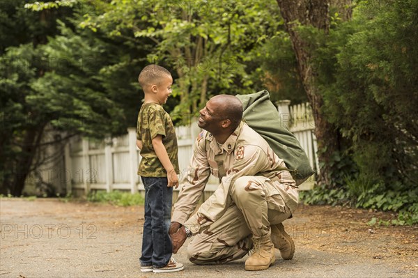 African American soldier tying shoelace for son