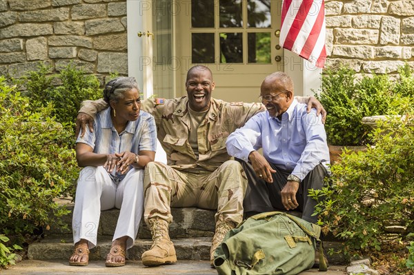 Soldier sitting on front stoop with parents