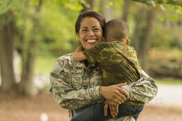 African American soldier mother carrying and hugging son