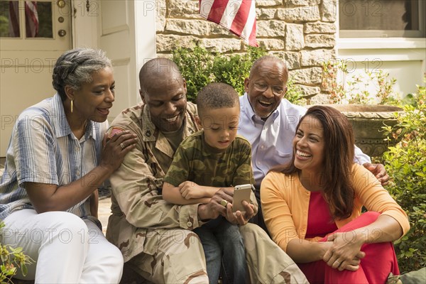 Soldier and multi-generation family looking down at cell phone