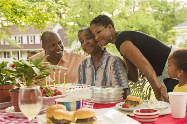 Multi-generation family celebrating with cake at picnic