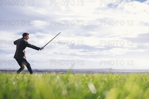 Caucasian man holding sword in field