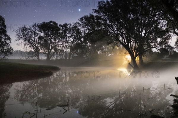 Sunrise through mist clouds in rural field