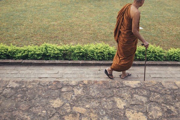 Monk walking with cane