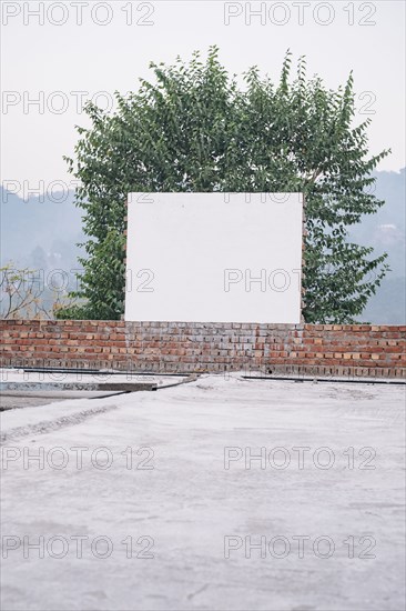 Blank board on brick wall near tree