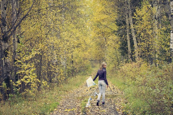 Woman carrying kite on dirt path