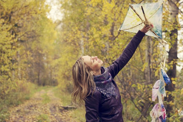 Woman holding kite in forest