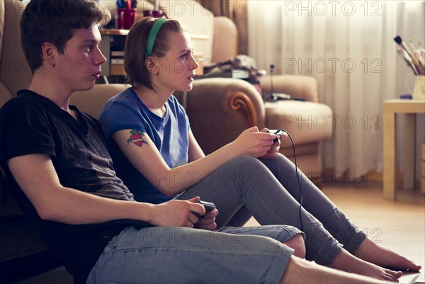Couple playing video games on living room floor