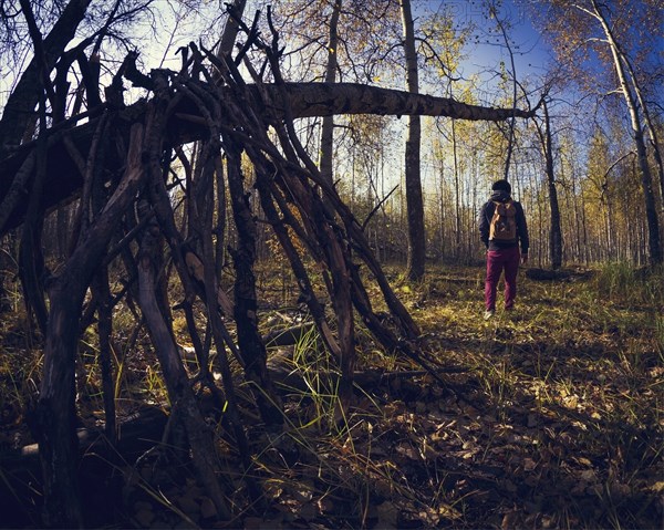 Man standing near wooden shelter in forest
