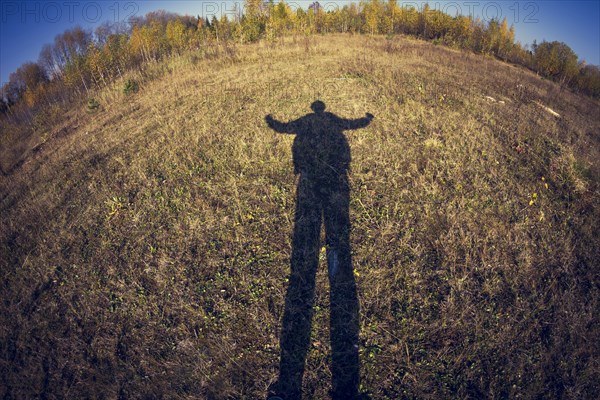 Fish-eye lens view of shadow of man in field