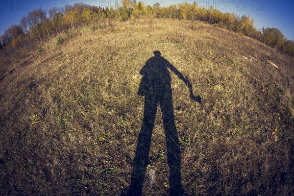 Fish-eye lens view of shadow of man in field