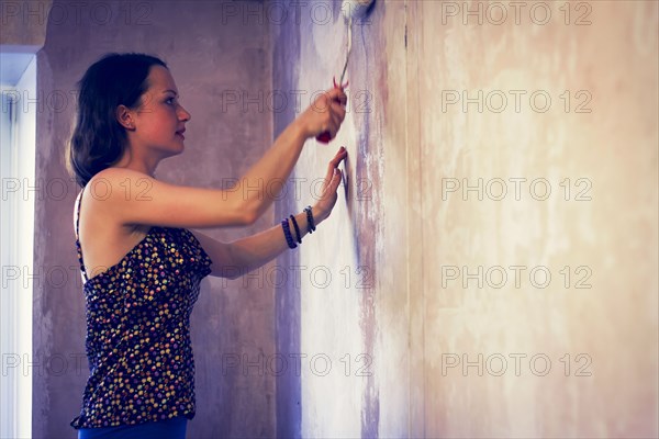 Woman painting wall with paint roller