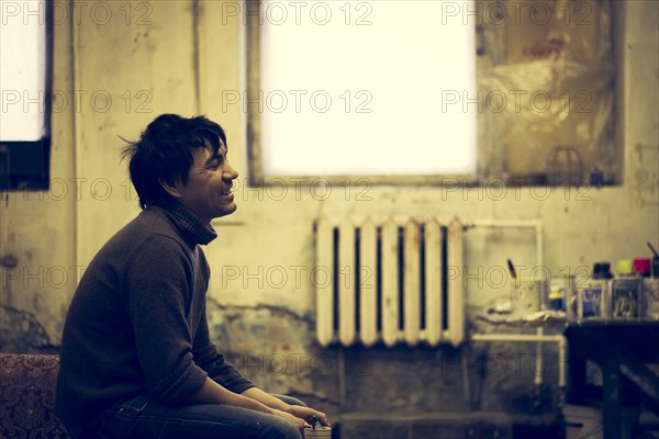 Asian man sitting in bedroom