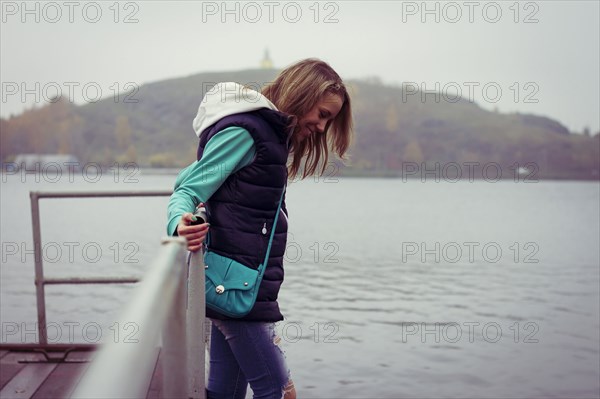 Caucasian woman standing on dock over still lake