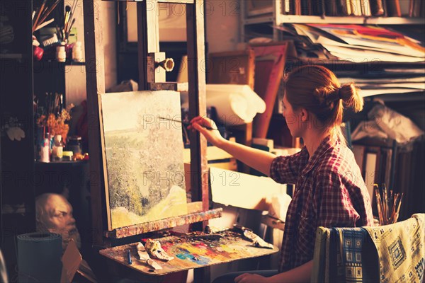 Caucasian artist painting on canvas in studio