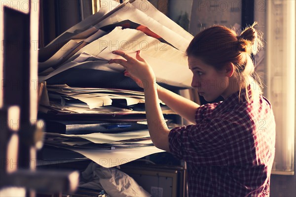 Caucasian artist sorting through papers in studio