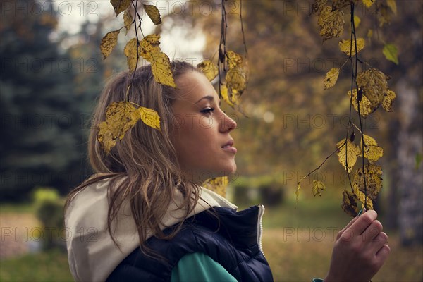 Caucasian woman walking under autumn leaves on tree