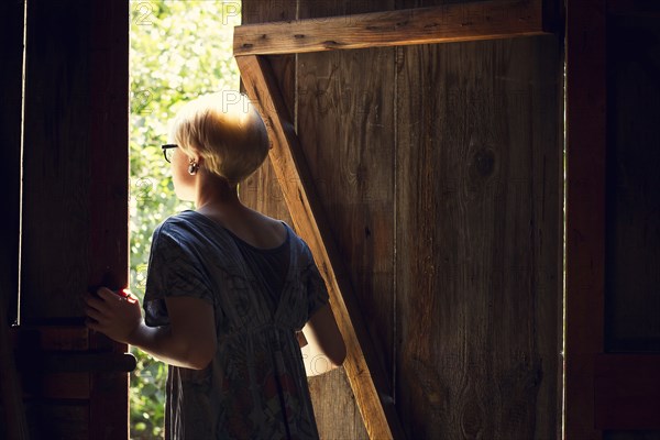 Caucasian woman looking out barn door