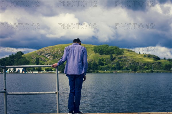 Caucasian man standing on dock at lake