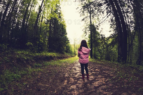 Caucasian girl walking on dirt path in forest
