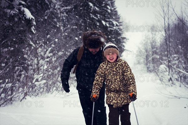 Caucasian father and daughter cross-country skiing on snowy road