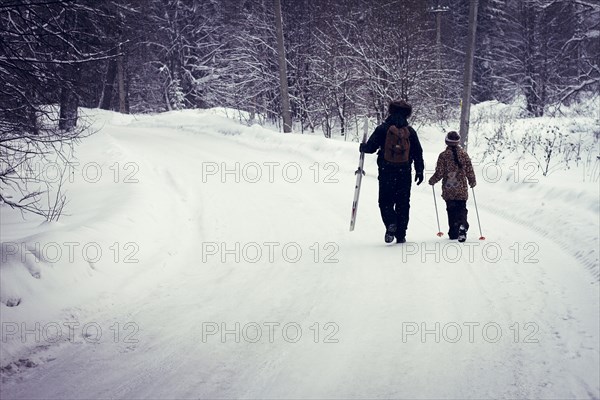 Caucasian father and daughter cross-country skiing on snowy road