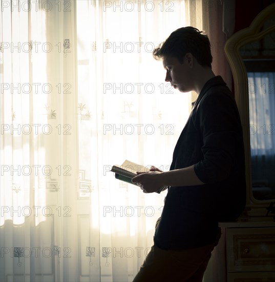 Caucasian man reading book near window