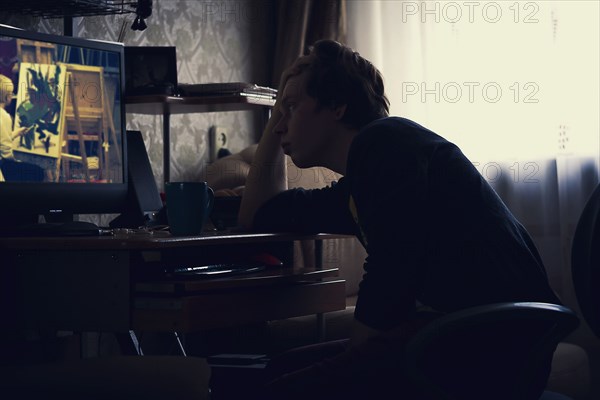 Caucasian man watching computer screen at desk