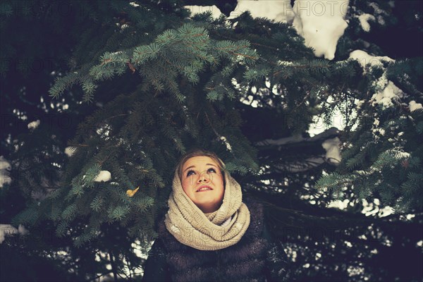 Caucasian woman standing under evergreen tree branches