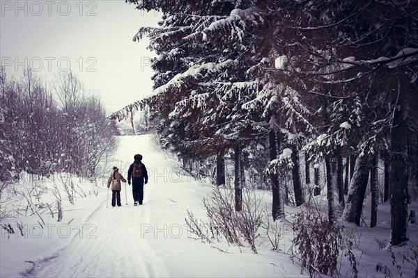 Caucasian father and daughter cross-country skiing on snowy road