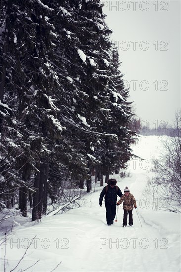 Caucasian father and daughter cross-country skiing on snowy road