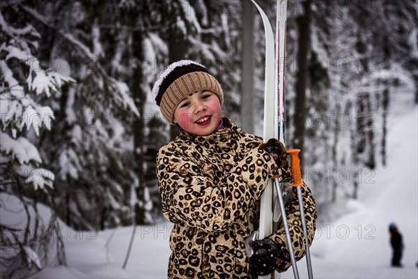 Caucasian girl carrying skis in forest