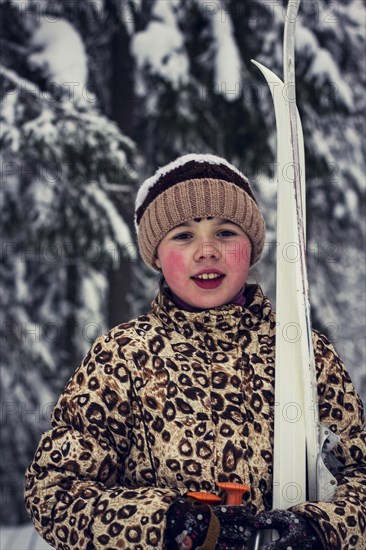 Caucasian girl carrying skis in forest