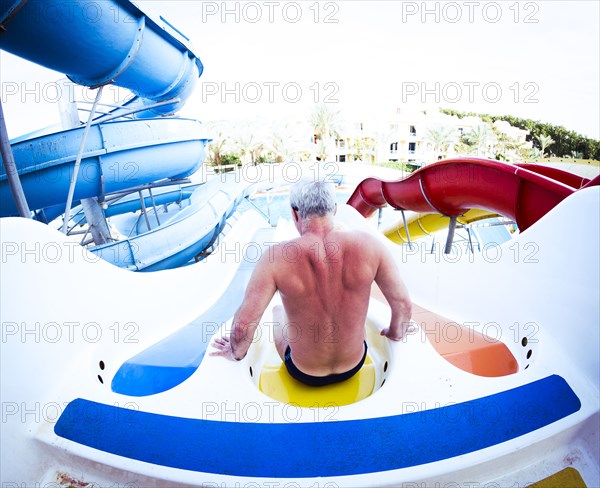 Older Caucasian man sitting on water slide