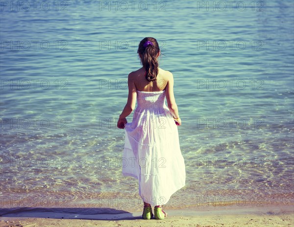 Caucasian girl wearing white dress on beach