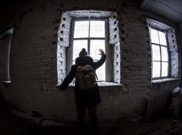 Caucasian man waving through illuminated window at night