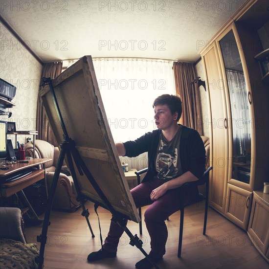 Caucasian artist painting in bedroom