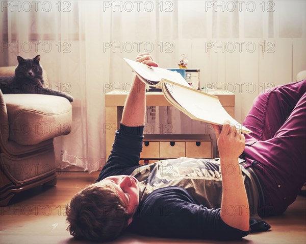 Caucasian man reading on living room floor