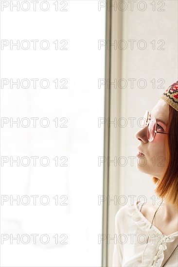 Caucasian woman wearing sunglasses near window