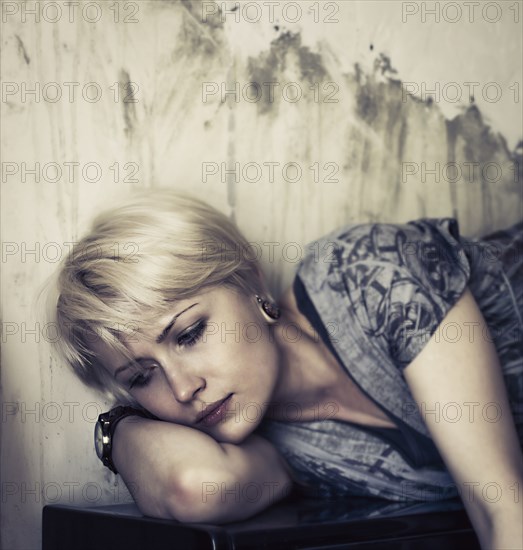 Pensive Caucasian woman laying on upright piano