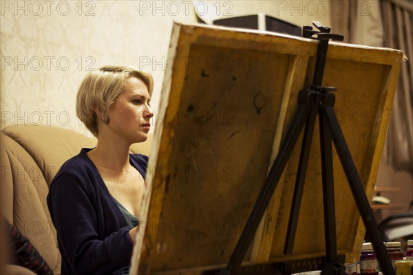 Caucasian woman painting on canvas in living room