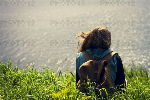 Caucasian woman laying in grass near lake