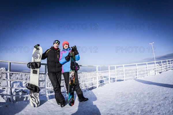 Caucasian snowboarders standing on mountaintop