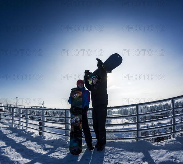 Caucasian snowboarders standing on snowy mountaintop