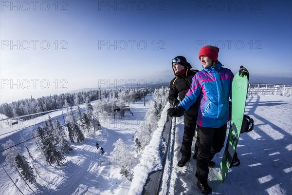 Caucasian snowboarders standing on snowy mountaintop