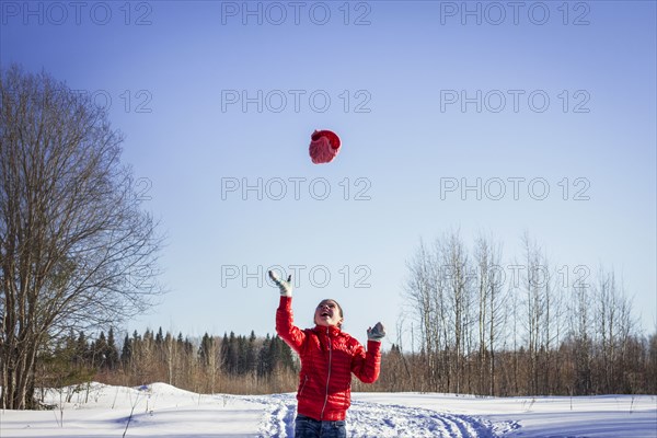 Caucasian girl throwing hat in snowy field