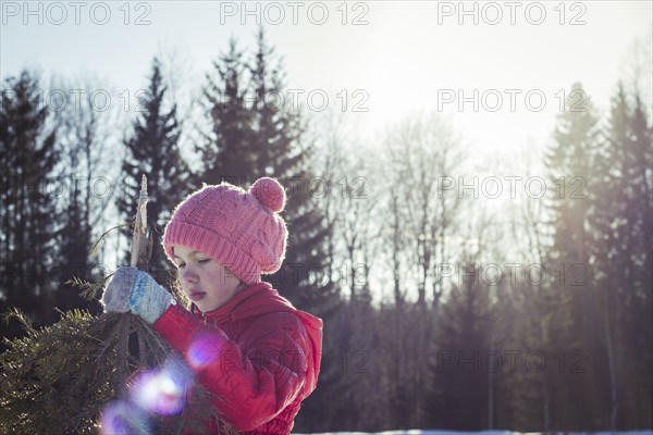 Caucasian girl holding tree branches in snowy field