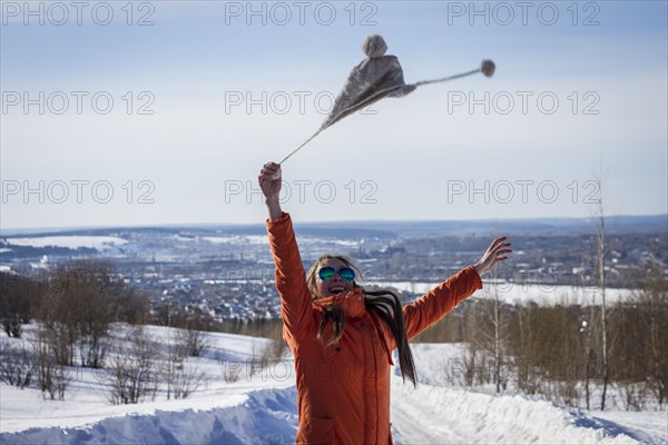 Caucasian woman swinging hat in snowy rural landscape